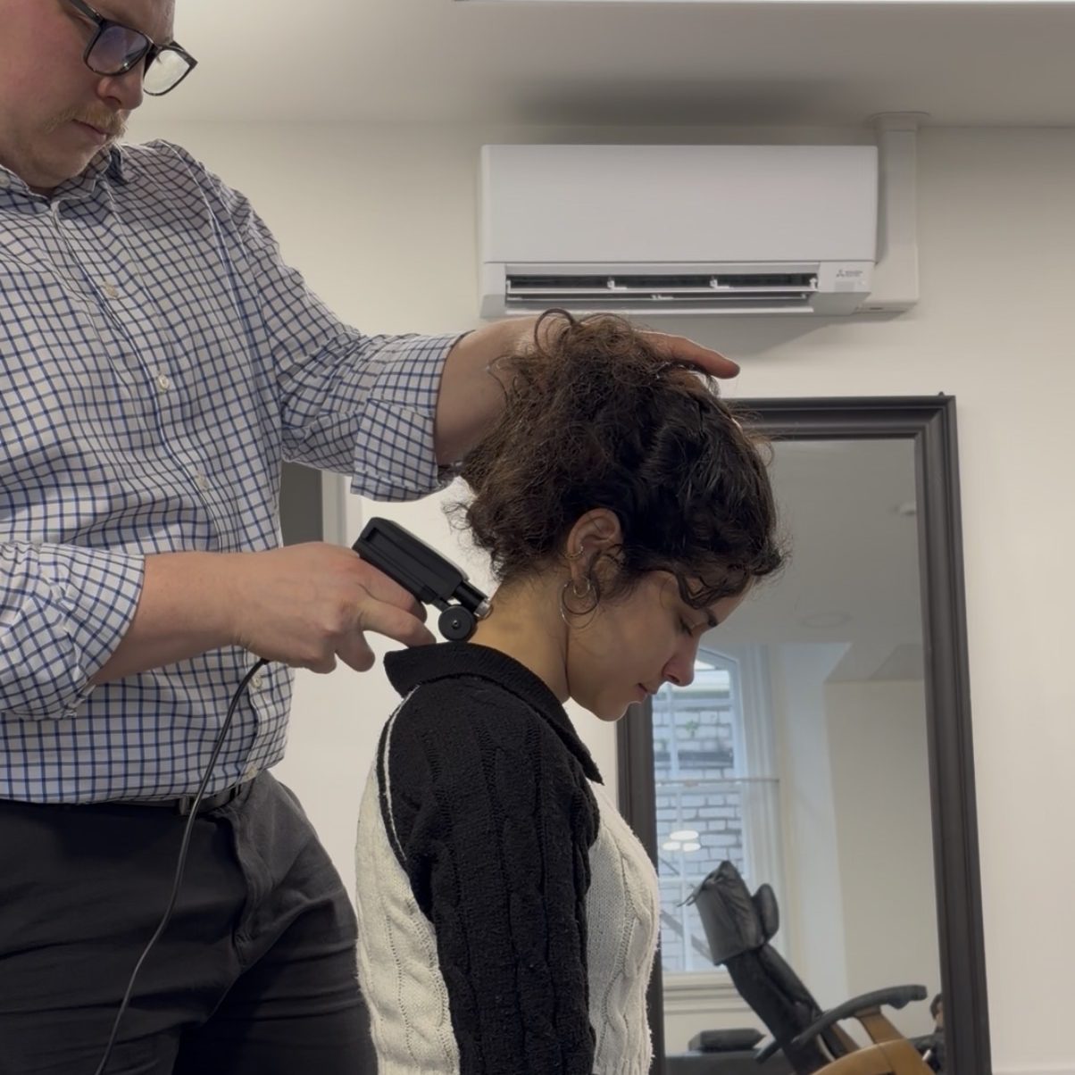 A chiropractor examining the upper cervical spine alignment of a seated client